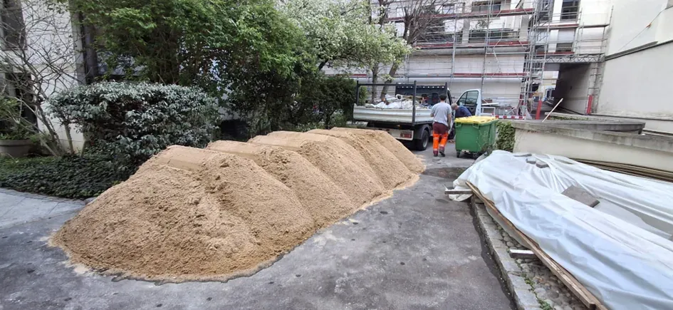 Approvisionnement du chantier en pied d'immeuble, sable et bennes de tri
