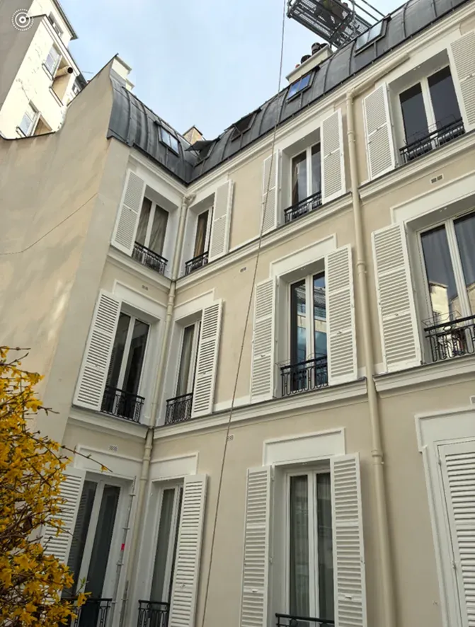 Façade sur cour du 172 boulevard Haussmann après ravalement : enduit crème, volets persiennés et toiture en zinc