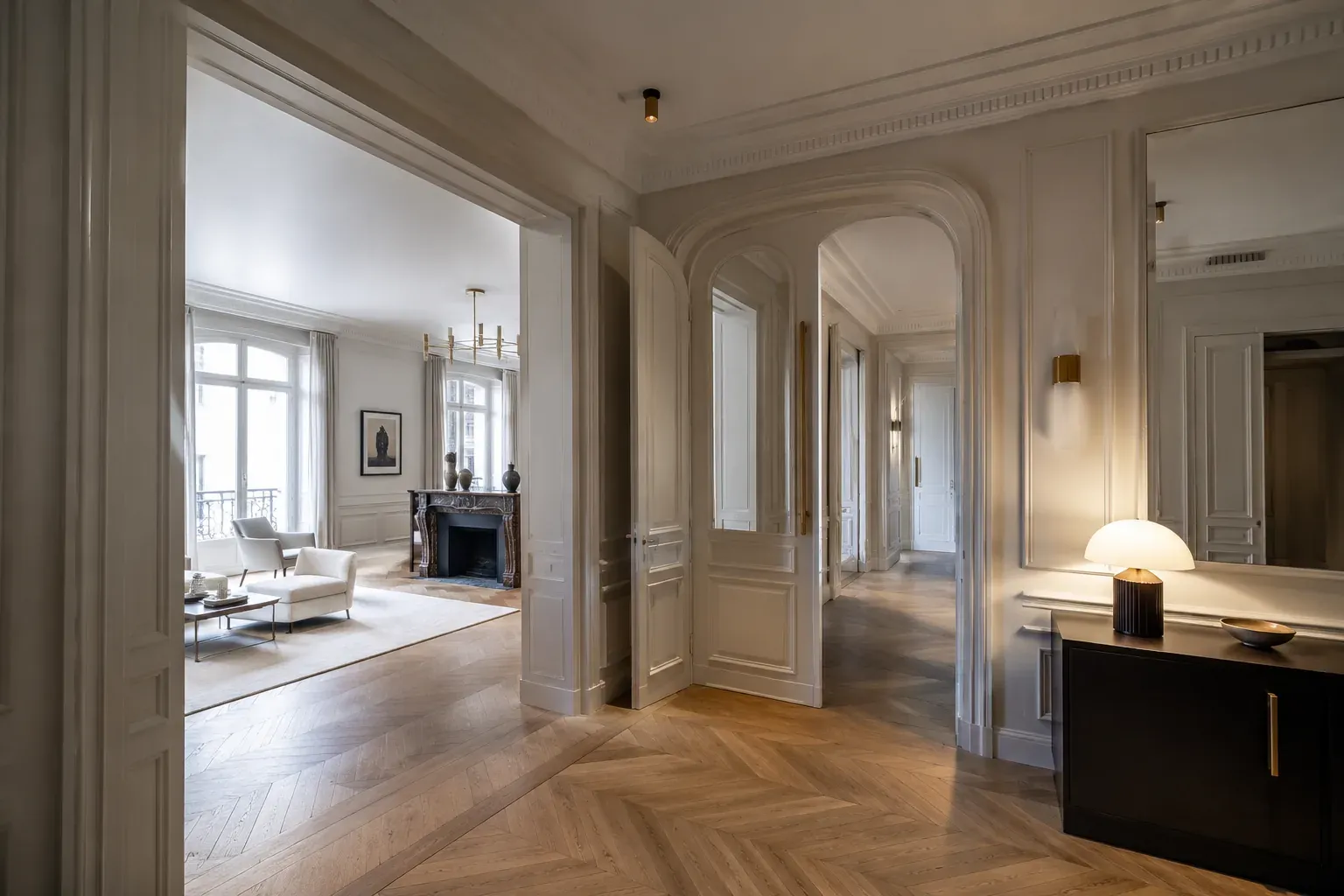 Intérieur haussmannien rénové par MCG Groupe : enfilade, parquet à bâtons rompus et cheminée en marbre