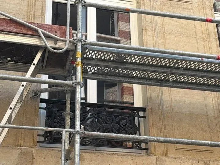 Reprise de façade en cours derrière l'échafaudage, maçonnerie mise à nu autour d'une baie